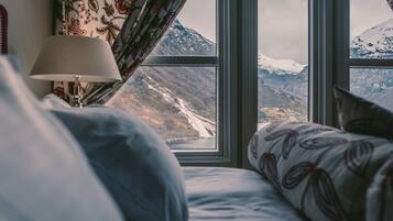 Cama com vista para uma paisagem montanhosa pela janela.
