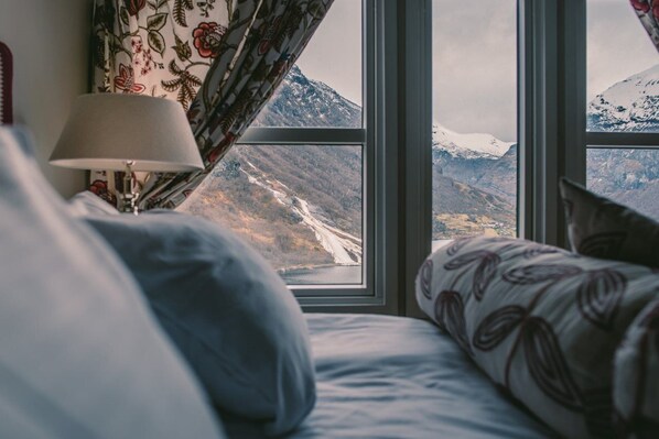 A bed with a view of a mountainous landscape through a window. - Hotel Union Geiranger (Stranda)