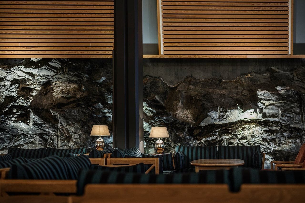 Un interior moderno con pared de roca, listones de madera y asientos tapizados a rayas.