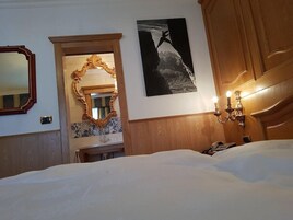 Camera d'albergo con un letto grande, uno specchio, un quadro appeso e una testiera in legno.