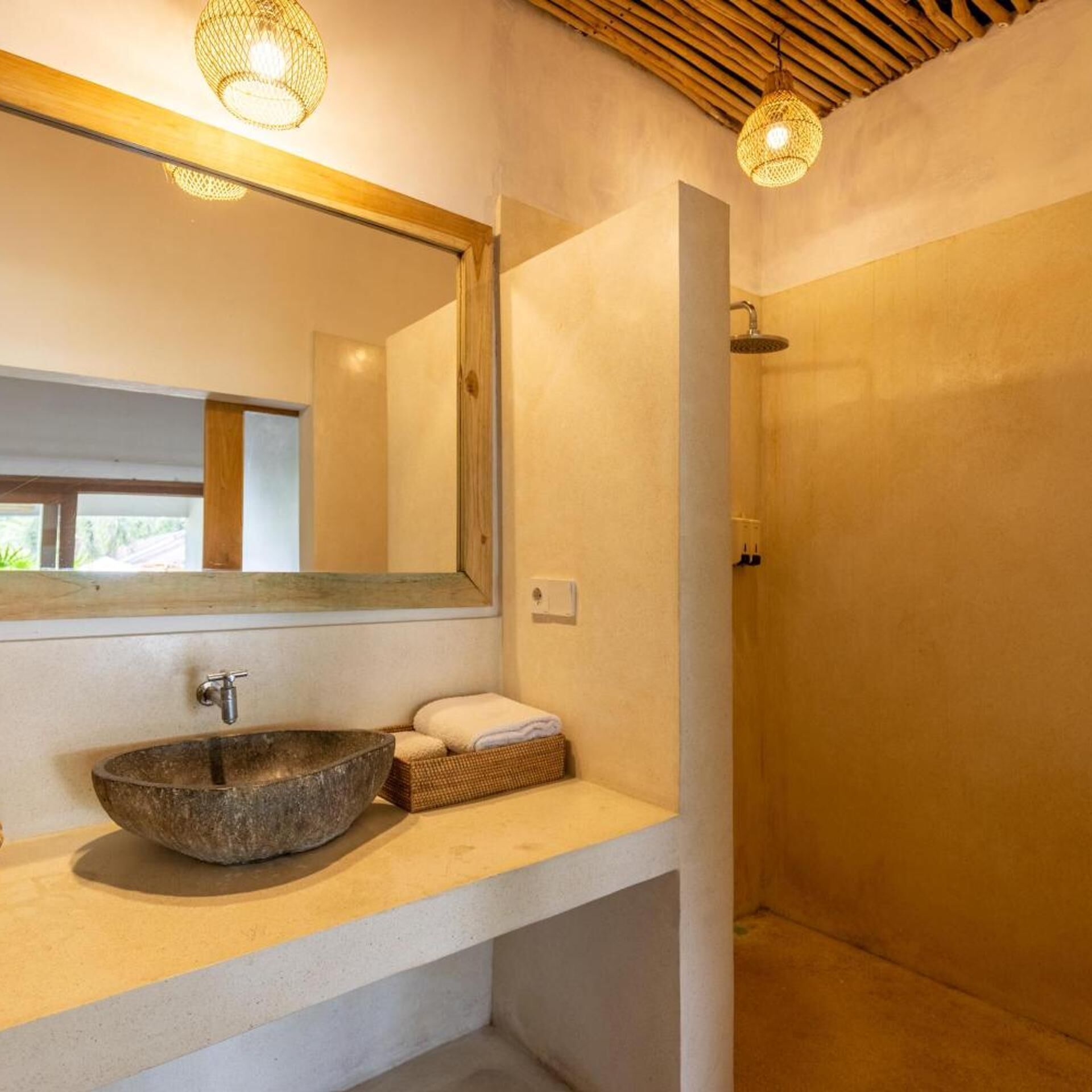 A modern bathroom with a stone sink, a large mirror, and a shower.