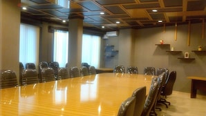 Une salle de conférence dotée d’une longue table en bois, de nombreuses chaises et d’un plafond au design moderne.