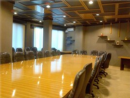 Uma sala de conferência com uma longa mesa de madeira, várias cadeiras e um design moderno no teto.