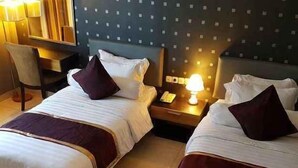 Une chambre d’hôtel avec deux lits, un bureau et une chaise.