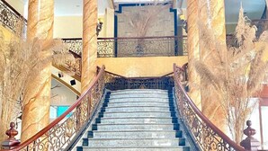 Un magnifique escalier, orné de colonnes de marbre et de rampes ouvragées, menant à l’étage supérieur.