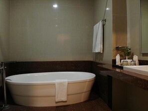 A modern bathroom with a freestanding bathtub, a sink, and a mirror. - Muara Hotel and Mall Ternate (Ternate)