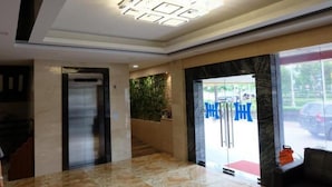 A hotel lobby with a reception desk, a staircase, and a large window with a view of the outside. - Holiday Hotel Batam (Batam)