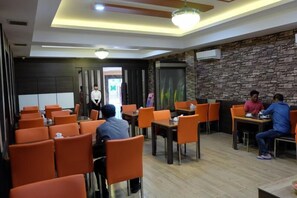 Un restaurant avec des chaises et des tables orange, et un mur en pierre.