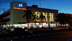 A Holiday Hotel building with illuminated signage, a visible entrance, and a parking area with cars. - Holiday Hotel Batam (Batam)