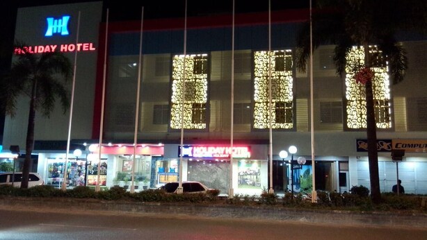 A Holiday Hotel building with illuminated signage, a visible entrance, and a parking area in front. - Holiday Hotel Batam (Batam)