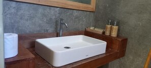 A bathroom with a white rectangular sink, a wooden vanity, and two bottles of soap. - Rua Beach Resort Sumba Island (Wanokaka)