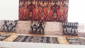 A room with a bed featuring a patterned bedspread and multiple pillows with animal prints.