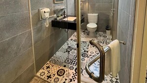 A modern bathroom with a glass shower enclosure, a sink with a mirror above, and a toilet. - Kaloka Airport Hotel (Sumbawa Besar)
