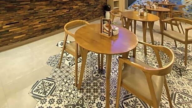 Un restaurante con mostrador de piedra, sillas de madera y una televisión.