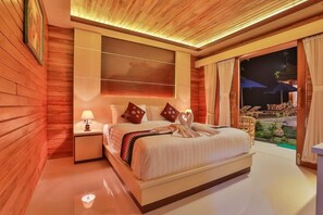 Habitación de hotel con una cama grande, una mesita de noche, un televisor montado en la pared y vistas al exterior.