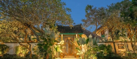 A traditional building with a thatched roof, surrounded by lush greenery and a well-maintained garden.