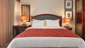 A hotel room with a large bed, two bedside lamps, a desk, and a wardrobe.