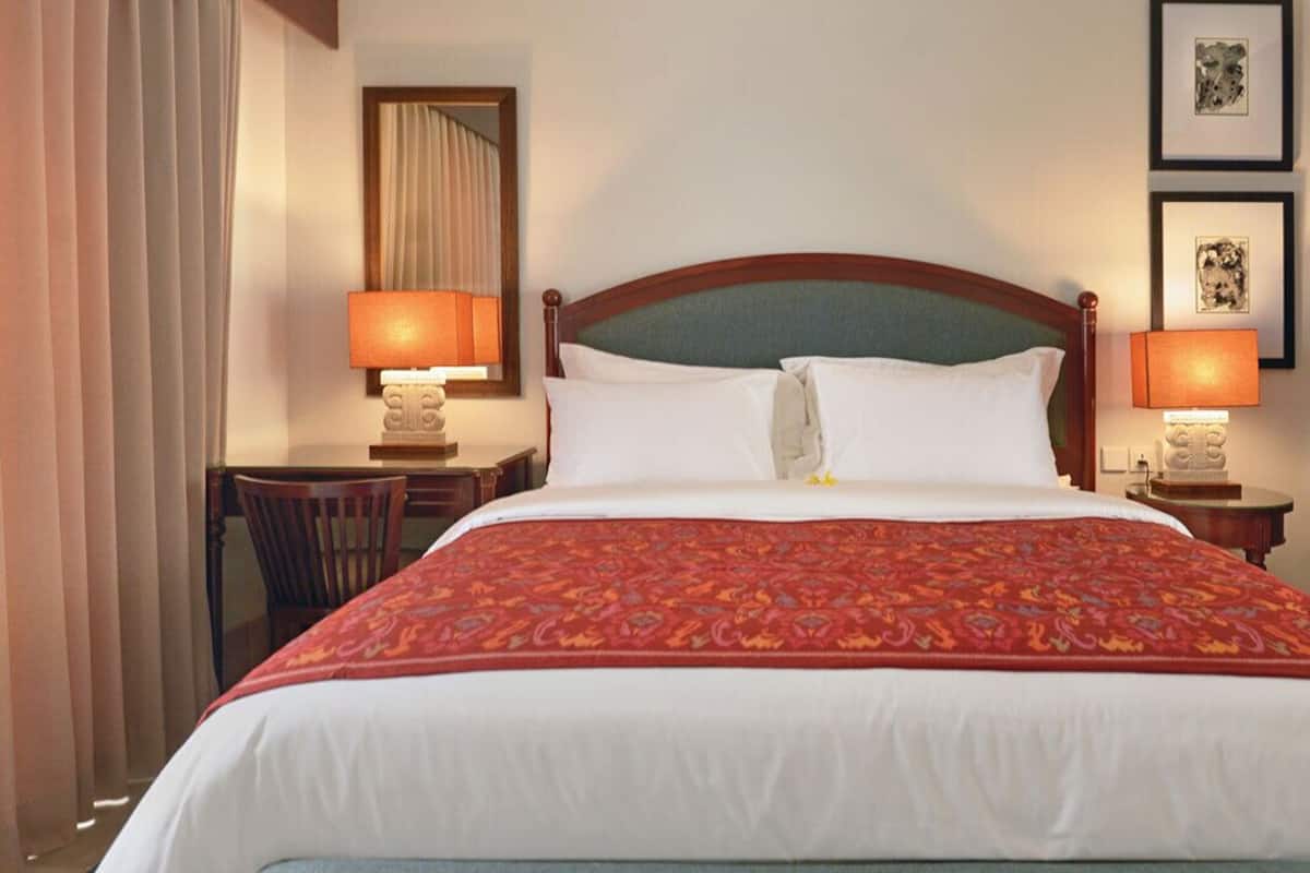 A hotel room with a large bed, two bedside lamps, a desk, and a wardrobe.