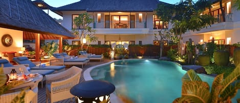 A resort with a swimming pool, lounge chairs, and a traditional building.