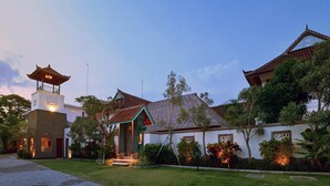A traditional building with a pagoda-style tower, a covered entrance, and a well-maintained garden.