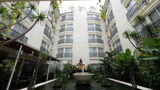 A courtyard with a central fountain, surrounded by potted plants and a building with balconies. - Hotel ZIA Bali - Kuta (Kuta)
