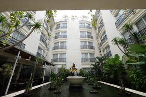 A courtyard with a central fountain, surrounded by potted plants and a building with balconies. - Hotel ZIA Bali - Kuta (Kuta)