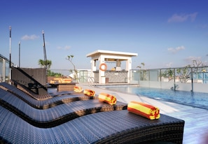 Zona de piscina en la azotea con sillones de descanso y un flotador.