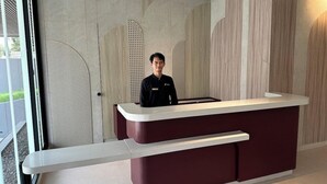 A reception desk with a modern design, a nameplate, and a security camera above it. - Fulmar Pasteur (Bandung)