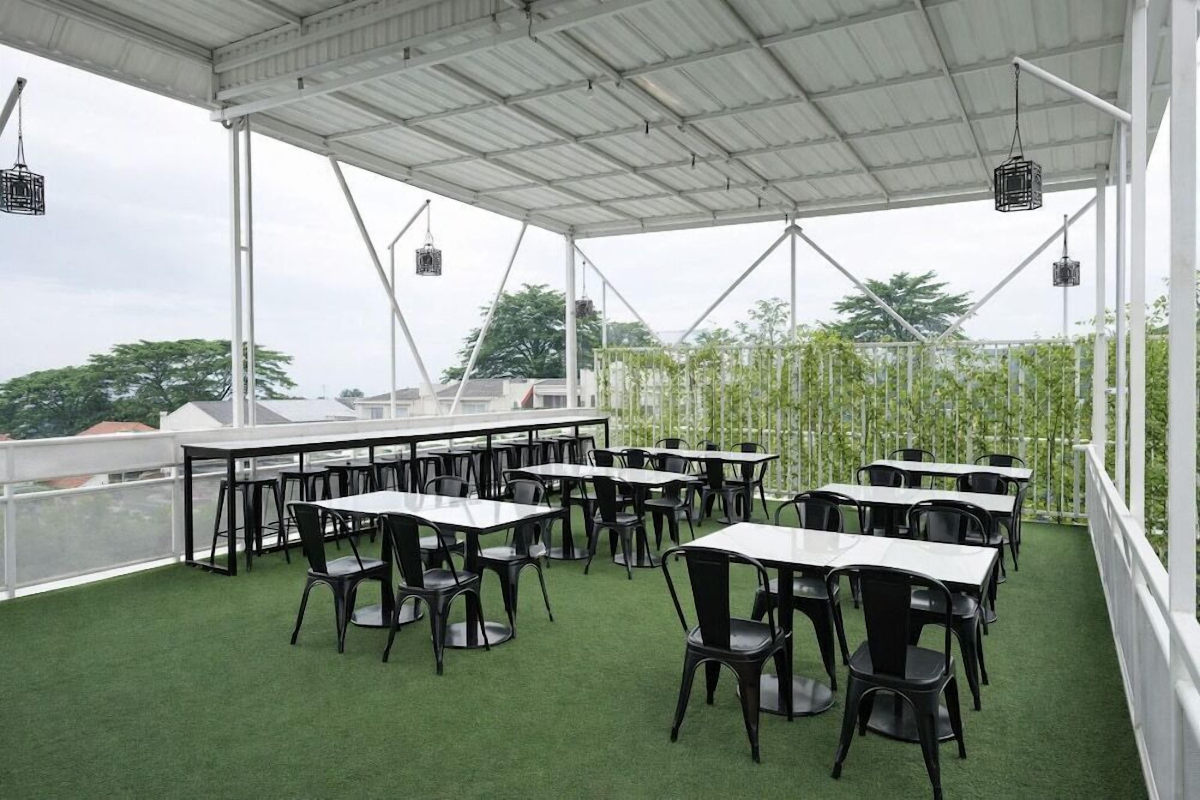 Un espace de restauration en plein air avec des tables et des chaises, un toit blanc et une vue sur les arbres et les bâtiments.