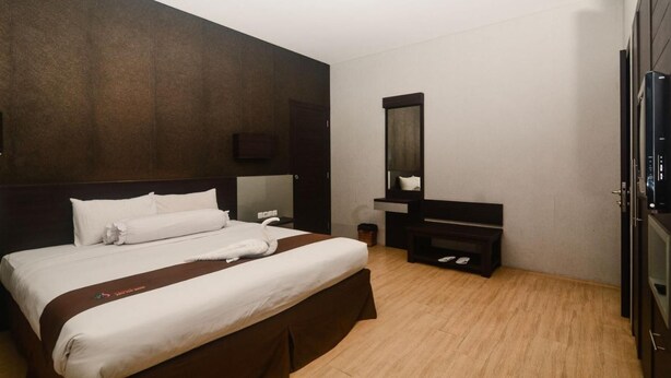 A hotel room with a large bed, a TV, a mirror, and a wardrobe. - Batu Suki Resort and Hotel (Batu)