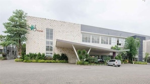 A modern hotel with a stone facade, a covered entrance, and a paved driveway. - Batu Suki Resort and Hotel (Batu)