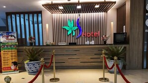 A hotel reception area with a modern design, featuring a reception desk, potted plants, and a red velvet rope barrier. - Batu Suki Resort and Hotel (Batu)