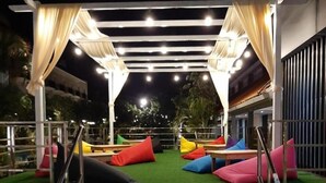 A covered outdoor seating area with steps leading up to it, surrounded by greenery. - Batu Suki Resort and Hotel (Batu)
