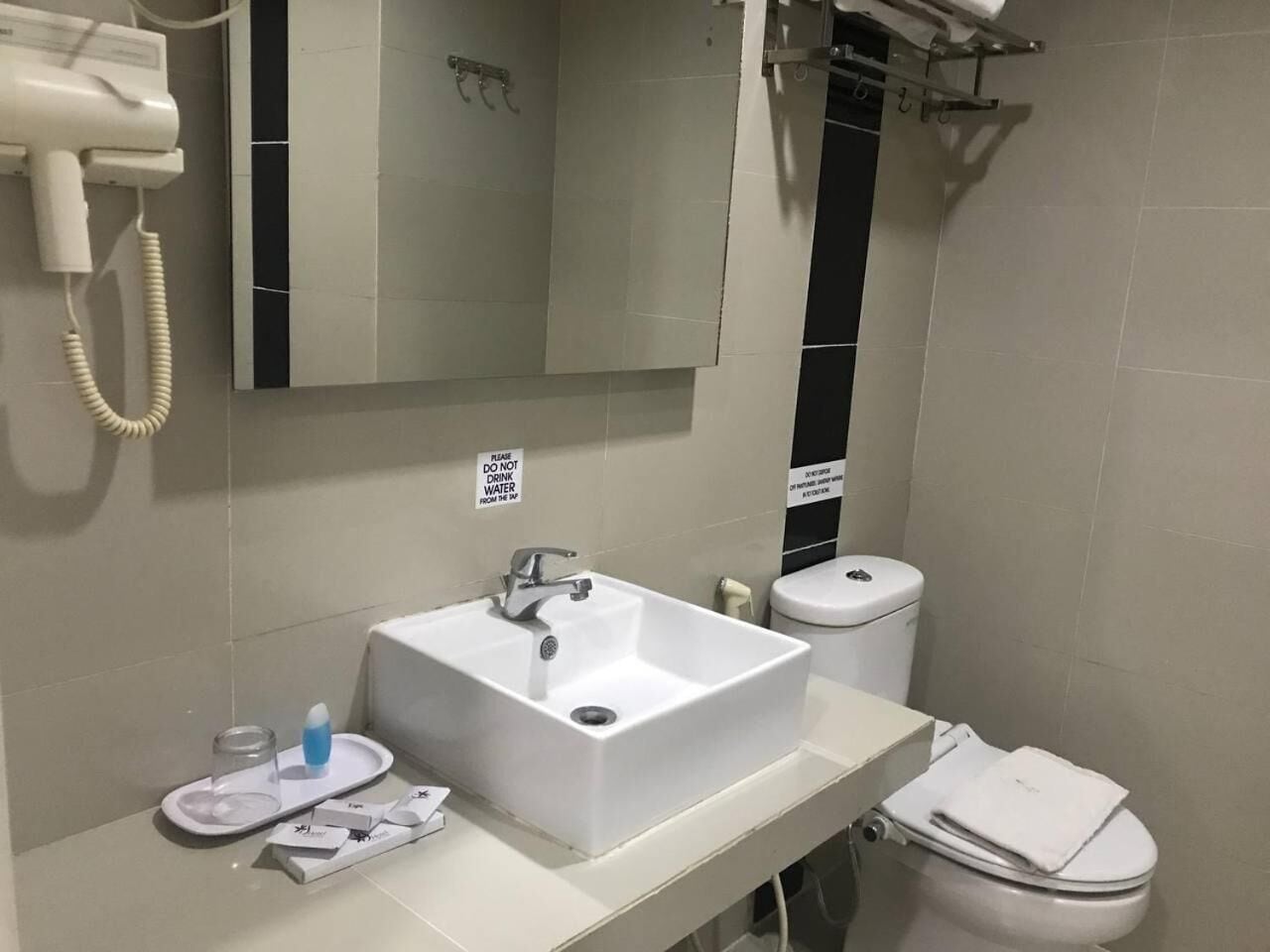 A bathroom with a white sink, a toilet, a mirror, and a hairdryer.