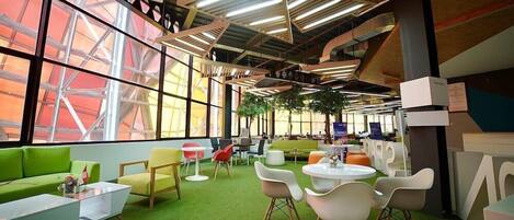 Un interior moderno con alfombra verde, muebles blancos y amarillos, y ventanas amplias.