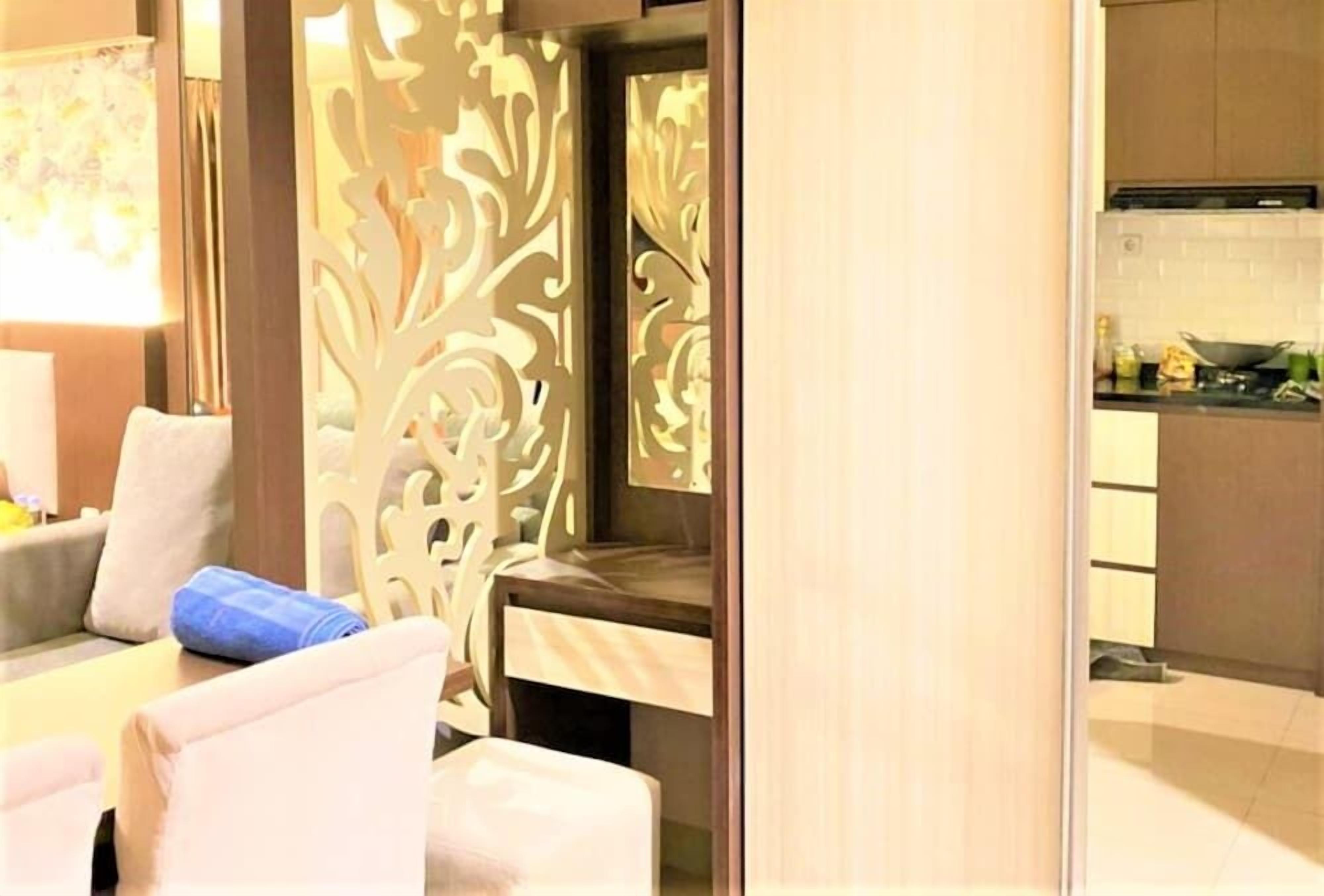 A modern hotel room with a sofa, a small table, and a decorative partition.