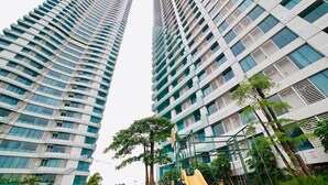 Un parque infantil con un tobogán amarillo y estructuras para escalar, rodeado de edificios residenciales altos.