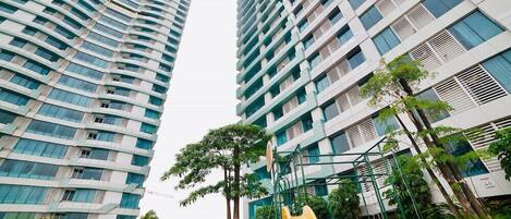 A playground with a yellow slide and climbing structures, surrounded by tall residential buildings.