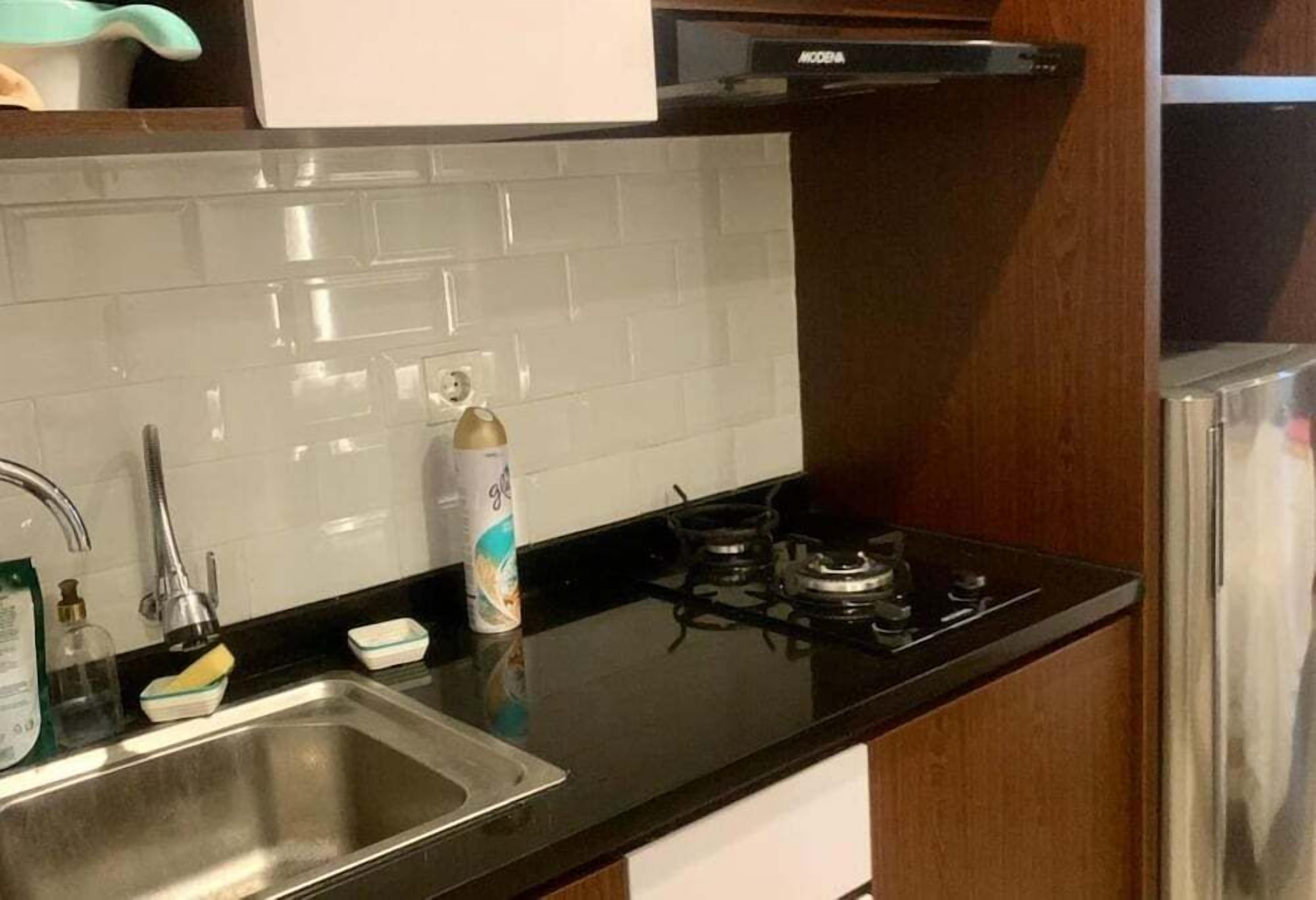 A kitchen with a stainless steel sink, a gas stove, and a white tiled backsplash.