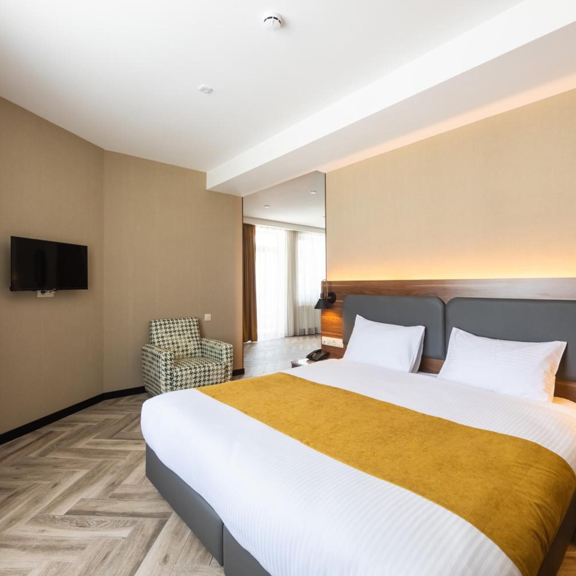 Une chambre d’hôtel avec un lit, une chaise, une télévision et une grande fenêtre.