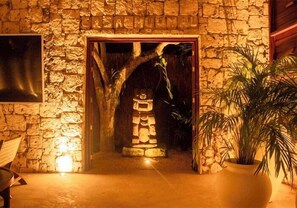 A stone-walled entrance with a traditional Japanese torii gate, a potted plant, and a wooden bench. - Zelune Luxury Lagoon Resort Bacalar Only Adults (Bacalar)