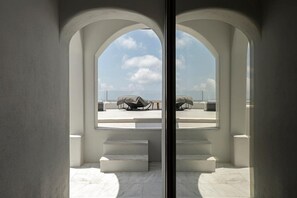 Une vue à travers une porte en verre, avec un design architectural moderne, qui révèle un ciel dégagé et un espace détente comprenant une table et des chaises.