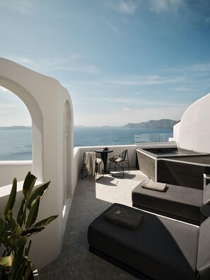 Un espace extérieur moderne, aménagé pour se détendre, avec vue sur la mer et les montagnes lointaines.