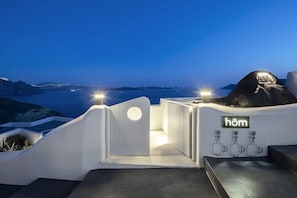 A modern hotel entrance with a view of the sea and a sign reading 'hôm'. - Hom Santorini - Adults Only (Santorini)