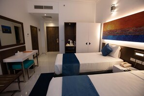 A hotel room with two beds, a desk, a chair, and a painting on the wall. - Gloria Aqua Park new Aswan (Aswan)