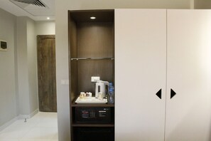Habitació d'hotel amb nevera, cafetera i panell de control.