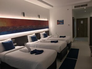 A hotel room with three beds, each with a white duvet and blue pillows, a large abstract painting on the wall, and a small picture frame. - Gloria Aqua Park new Aswan (Aswan)