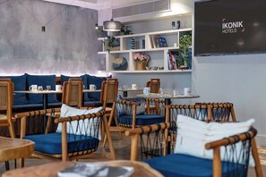 A modern hotel lobby with wicker furniture, a bookshelf, and a flat-screen TV displaying 'IKONIK HOTELS'. - Ikonik Jean Medecin (Nice)