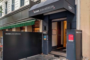 A hotel entrance with a black facade, a green awning, and a visible elevator. - Ikonik Jean Medecin (Nice)