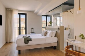 A modern hotel room with a bed, a desk, and a shower area. - Ikonik Jean Medecin (Nice)